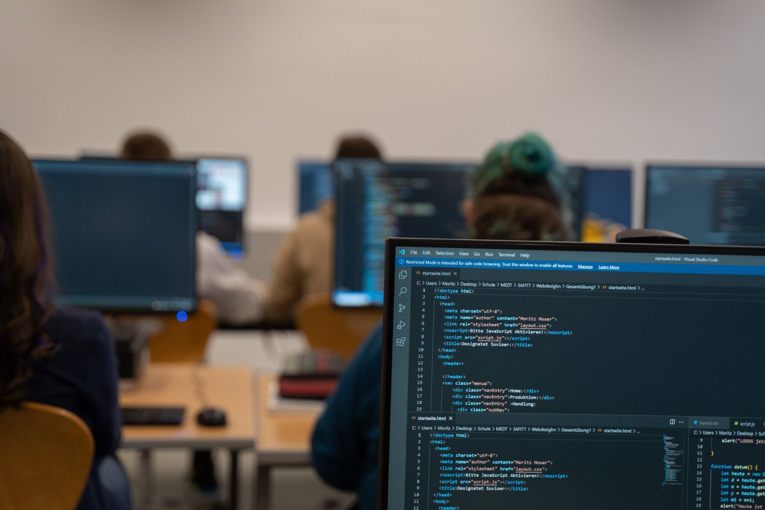EDV-Saal mit vielen Bildschirmen, im Vordergrund Programmcode