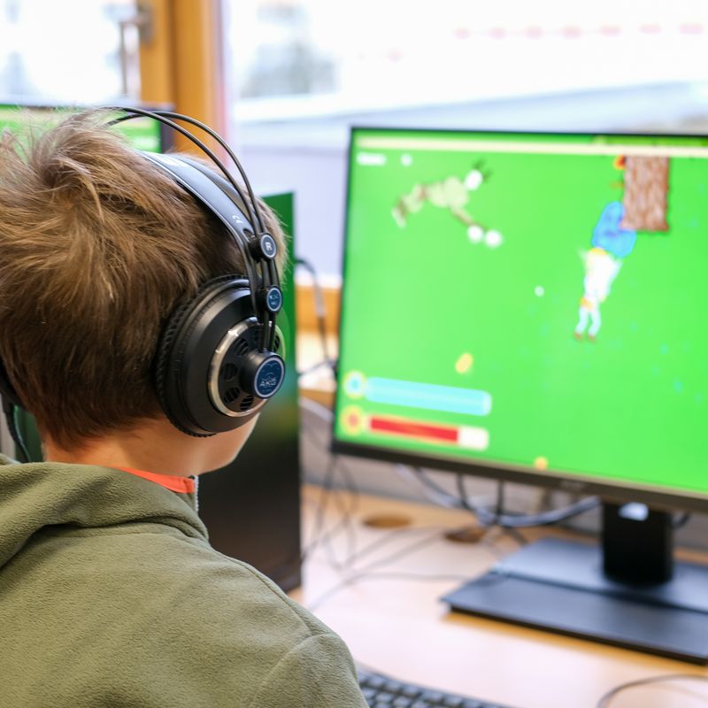 Schüler mit Kopfhörern testet ein selbst entwickeltes Spiel