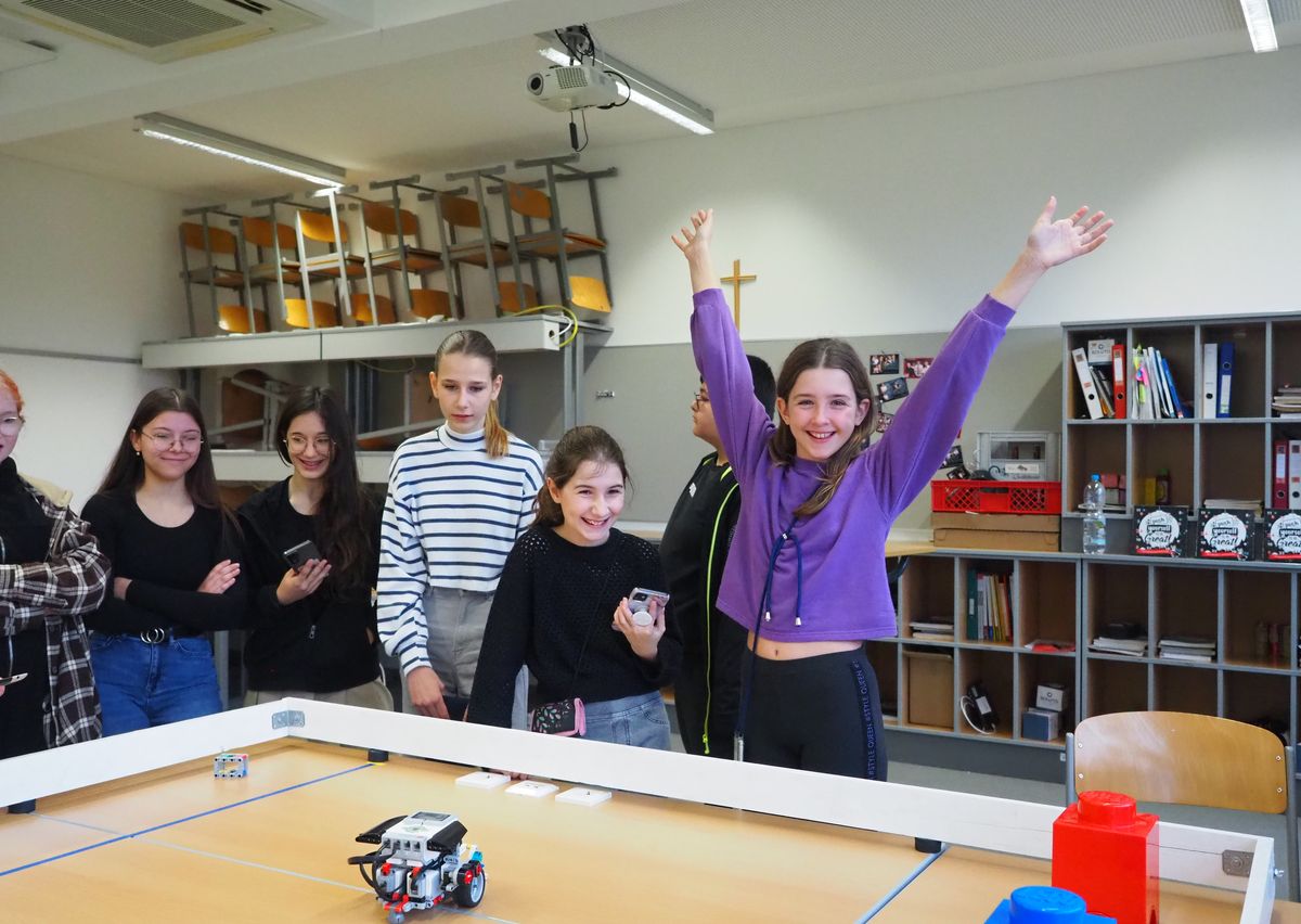 Mädchen jubeln, nachdem ihr selbst programmierter Roboter das Ziel erreicht hat