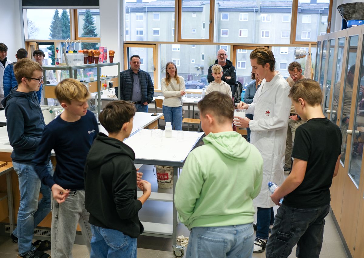 Besucher verfolgen einen Versuch im Chemielabor