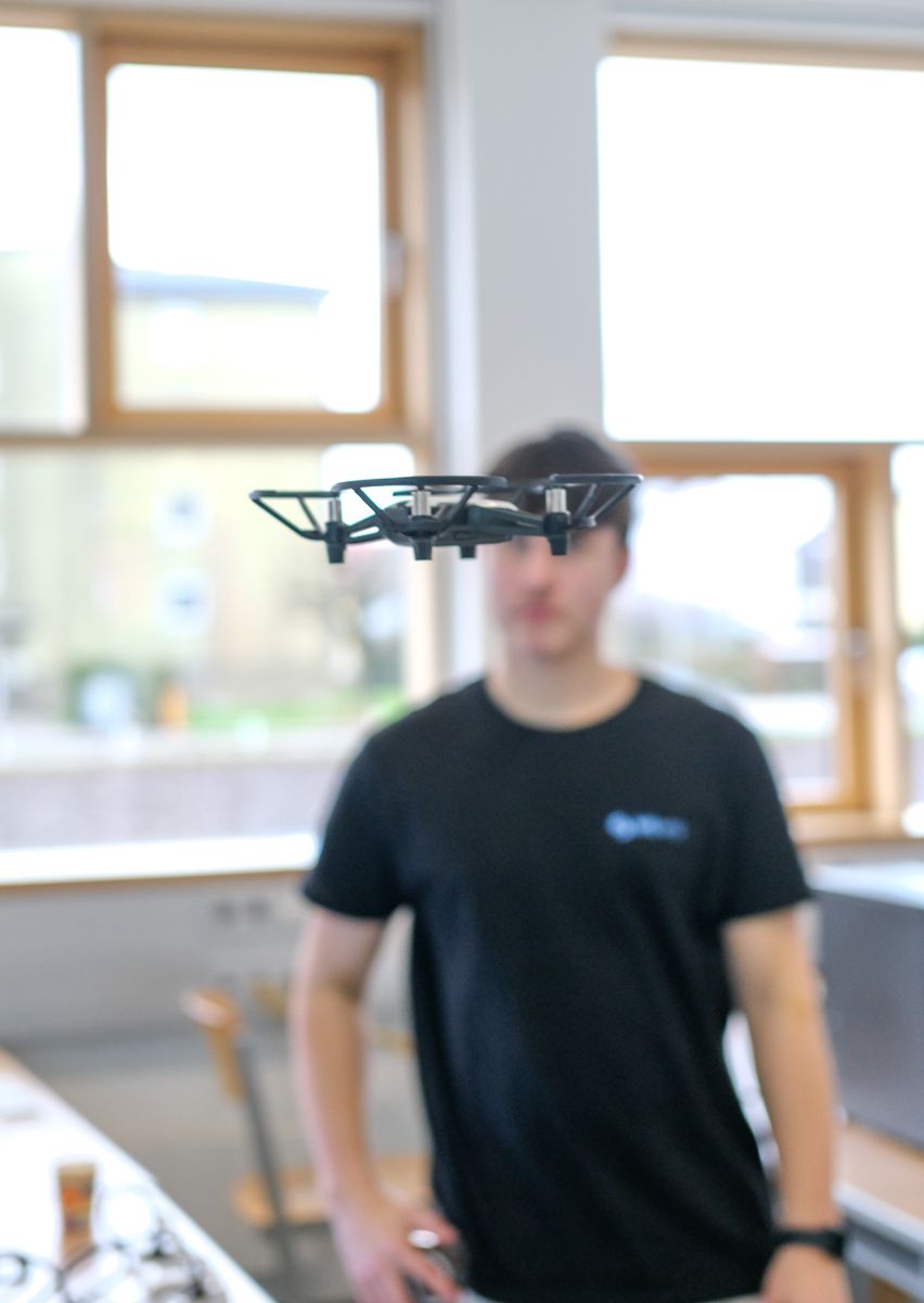Schüler steuert eine Drohne, die durch den Saal fliegt