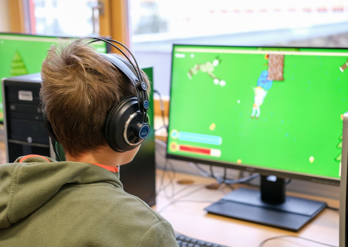 Junger Besucher mit Kopfhörern testet ein selbst entwickeltes Computerspiel