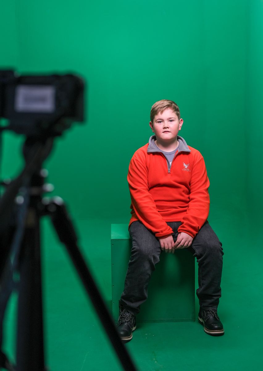 Besucher sitzt im Greenscreen-Studio vor der Kamera