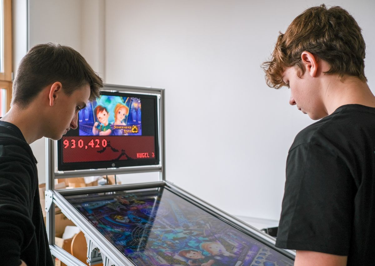 Zwei Schüler zeigen einen selbst gebauten digitalen Flipperautomaten
